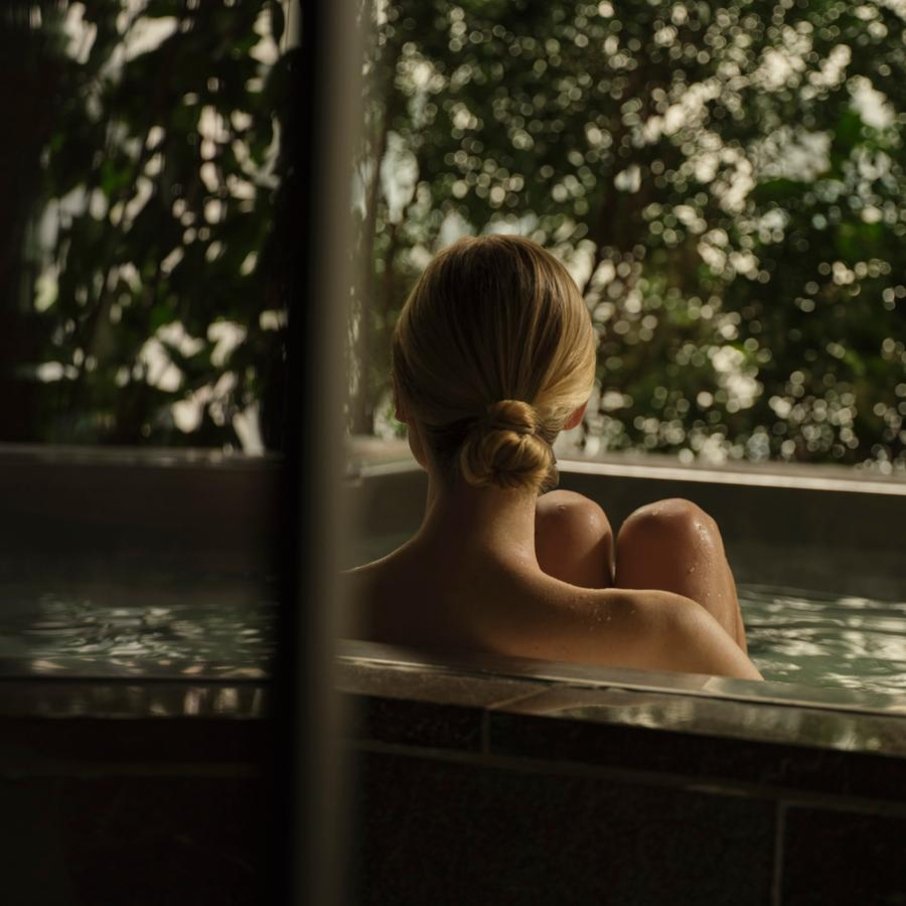 Woman relaxing in the Aman New York Spa pool surrounded by lush greenery and natural light
