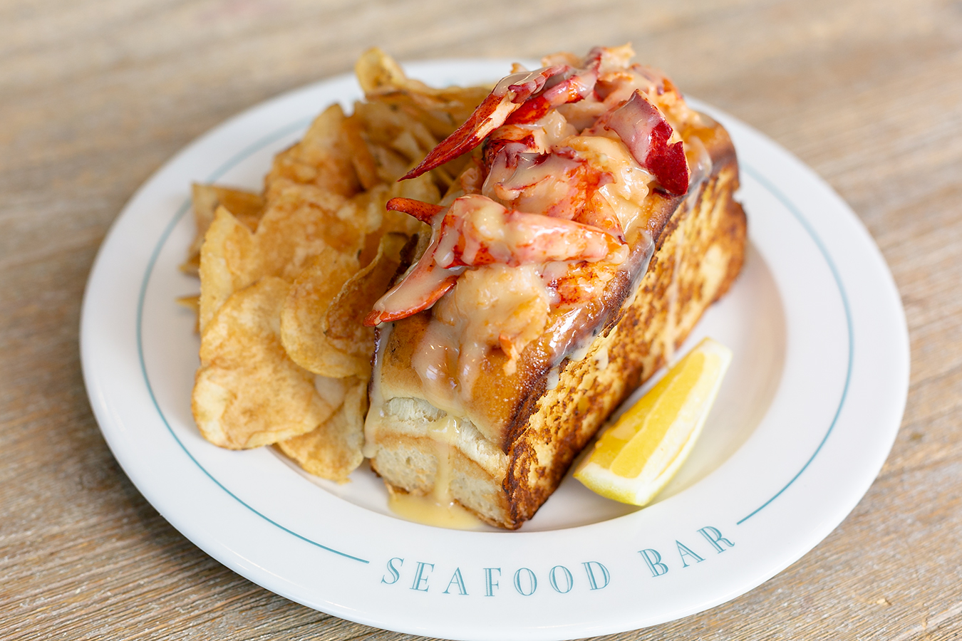 Saltie Girl butter lobster roll on branded Seafood Bar plate Back Bay Boston