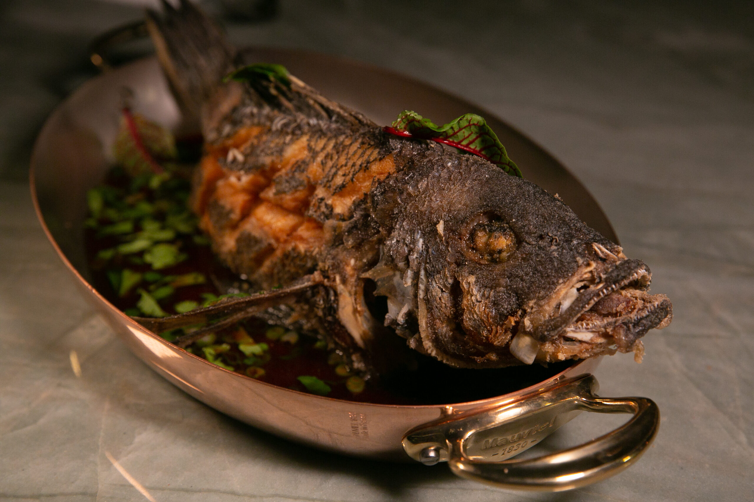 Whole crispy fried fish in copper pan at Saltie Girl Back Bay Boston