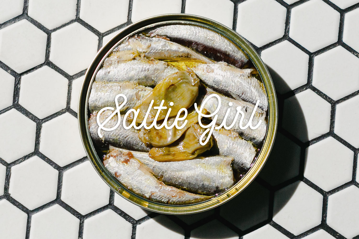 Tinned sardines on white hexagonal tile with Saltie Girl script logo Boston